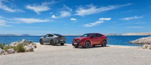 BMW iX4 M60 xDrive الكهربائية الحمراء من الأمام على شاطئ البحر