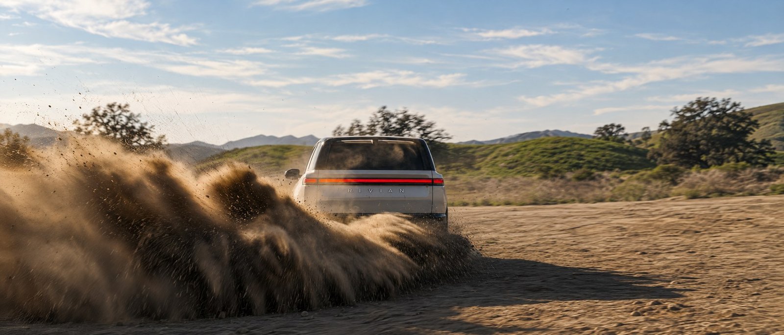 سيارة Rivian R2 الكهربائية أثناء القيادة على طريق رملي